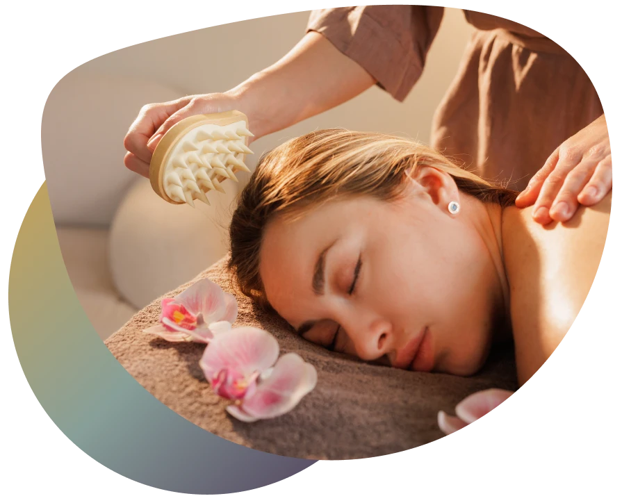 Woman relaxing in a spa setting with a hairbrush and orchid on her head.