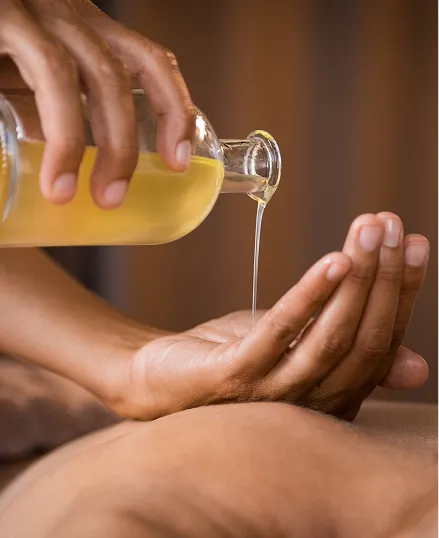 A person receiving a gentle aromatherapy massage with oil poured into their palm, ensuring a controlled and soothing experience.