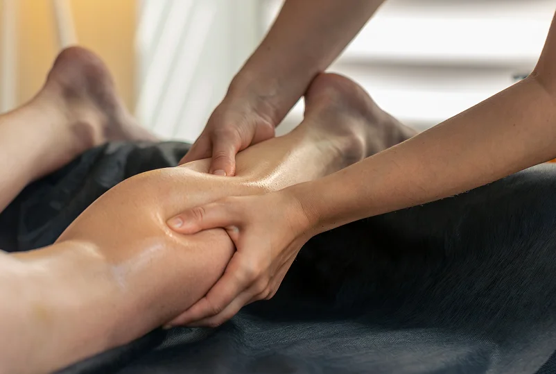 A person receiving a deep tissue massage on their lower back, with a therapist's hands gently working on the area.