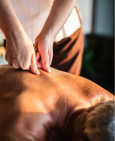 A person receiving a deep tissue massage on their back in a spa setting, with a therapist applying pressure to the neck and back.