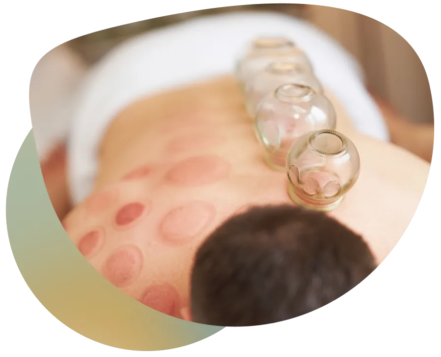 A person receiving a massage with oil being applied to their back, in a professional setting with a blurred background.