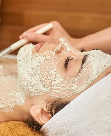 Woman receiving a facial massage on her forehead, with a white brush and a calming atmosphere.