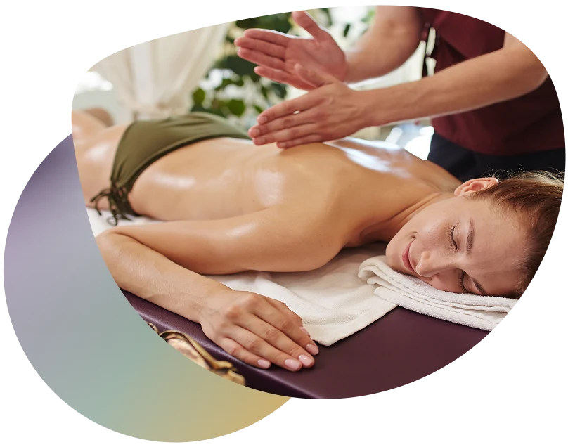 Woman receiving a massage on a table in front of a window with a white curtain.