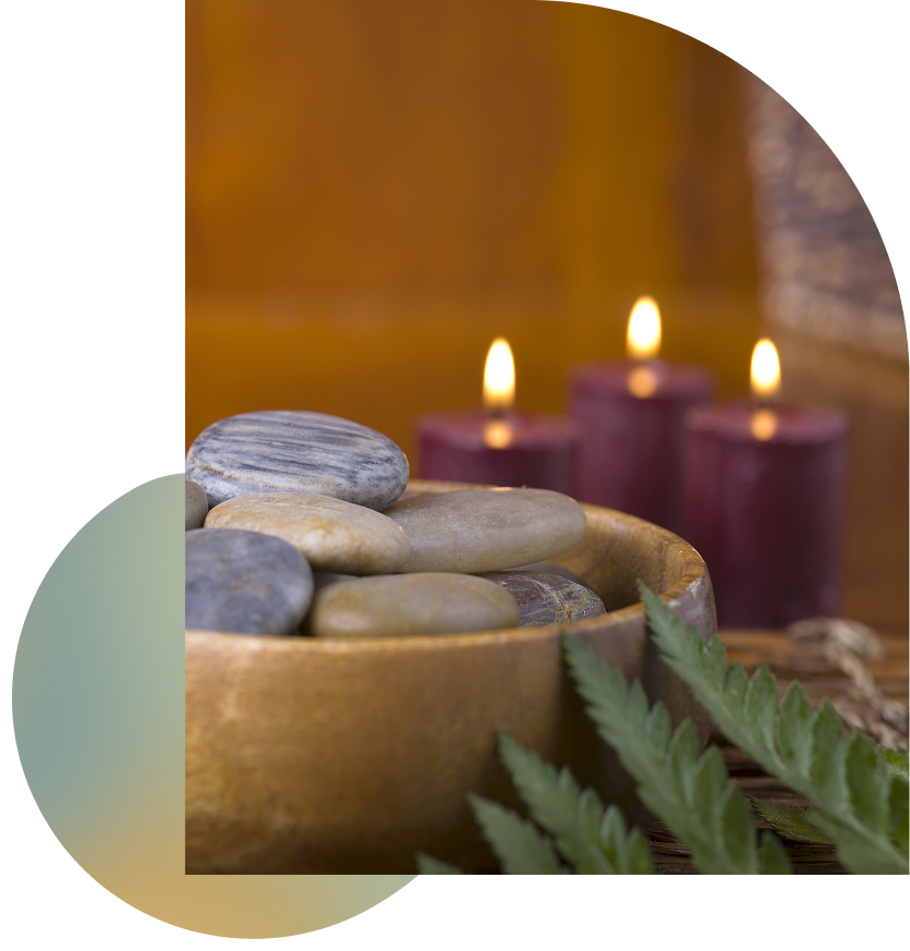 A serene setting with a wooden table, bowl with rocks, candles, and a green leaf, evoking a sense of natural tranquility.