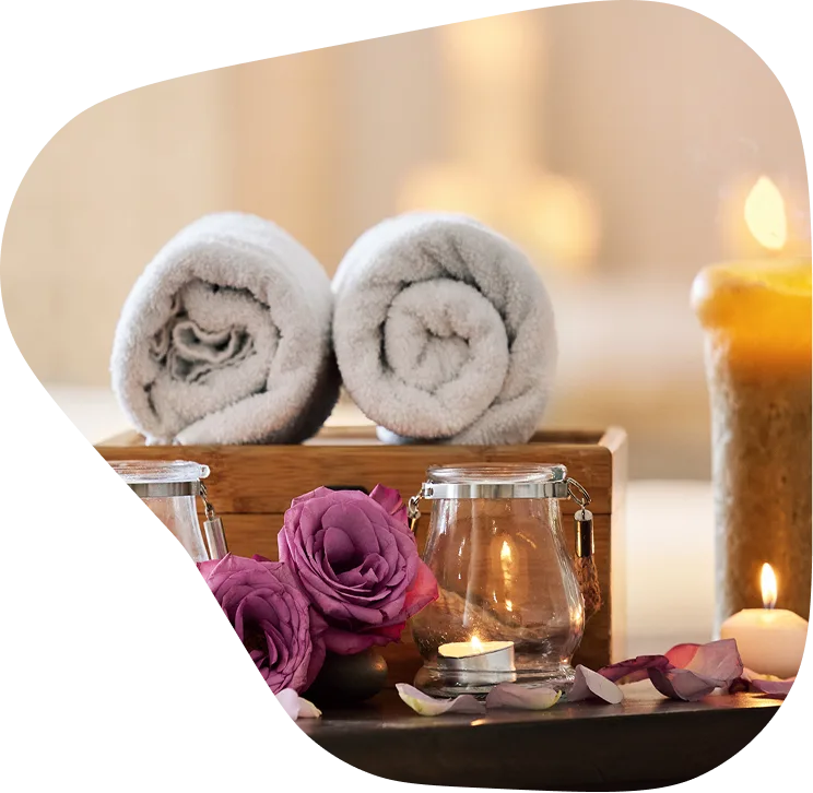 A serene and tranquil scene with a wooden box, candle, glass jar, and flowers on a wooden table, suggesting a peaceful and relaxing atmosphere in a spa or relaxation area.