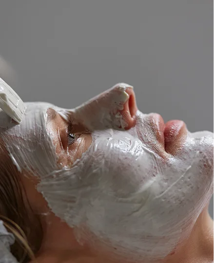 A person undergoing a deep tissue facial treatment, covered in a white plastic wrap with a bandage around their neck.