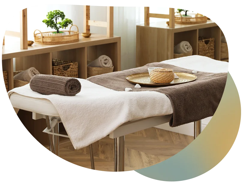 A serene spa setting with a wooden table, fresh green plants, and neatly arranged shelves, evoking a sense of tranquility and relaxation.