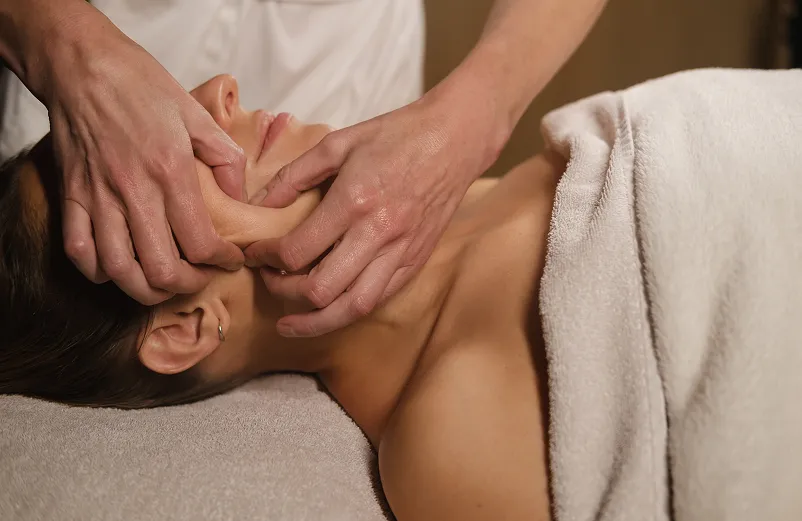 Woman receiving a massage from a therapist in a spa setting, promoting relaxation and calmness.