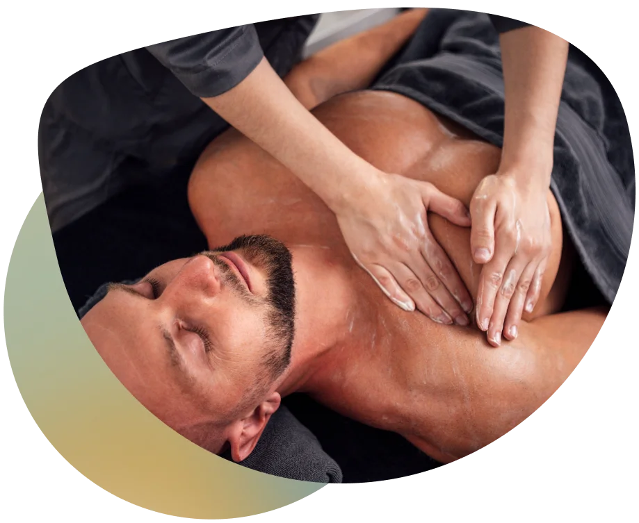 A man receiving a deep tissue massage, with a therapist applying oil to his back.